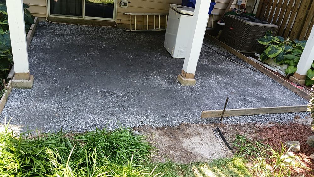 A patio is being built in the backyard of a house.