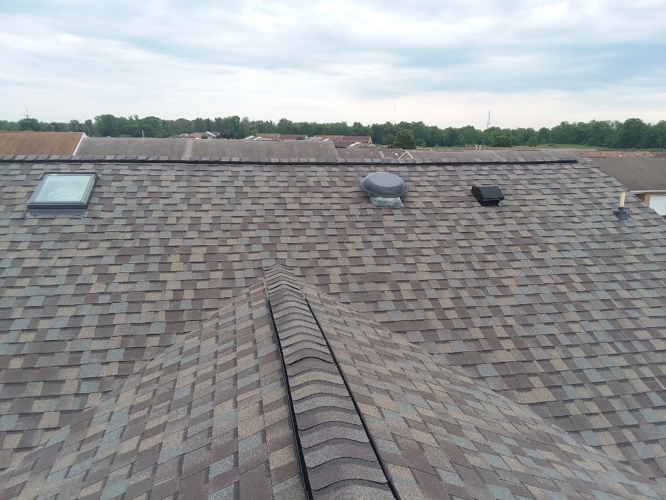 A roof with shingles and a skylight on it.