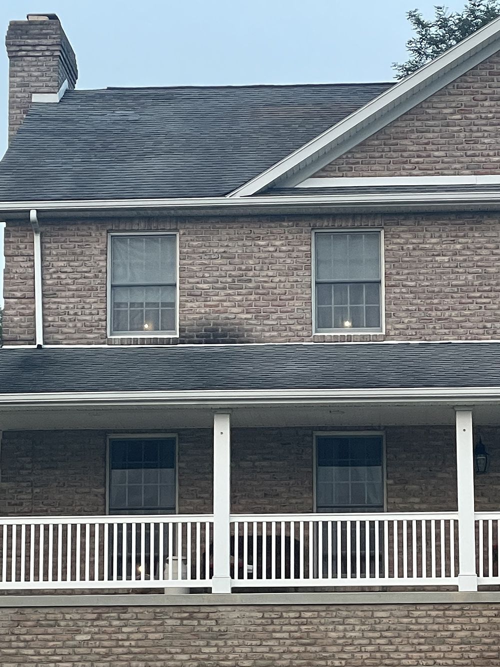 A brick house with a porch and a white railing.