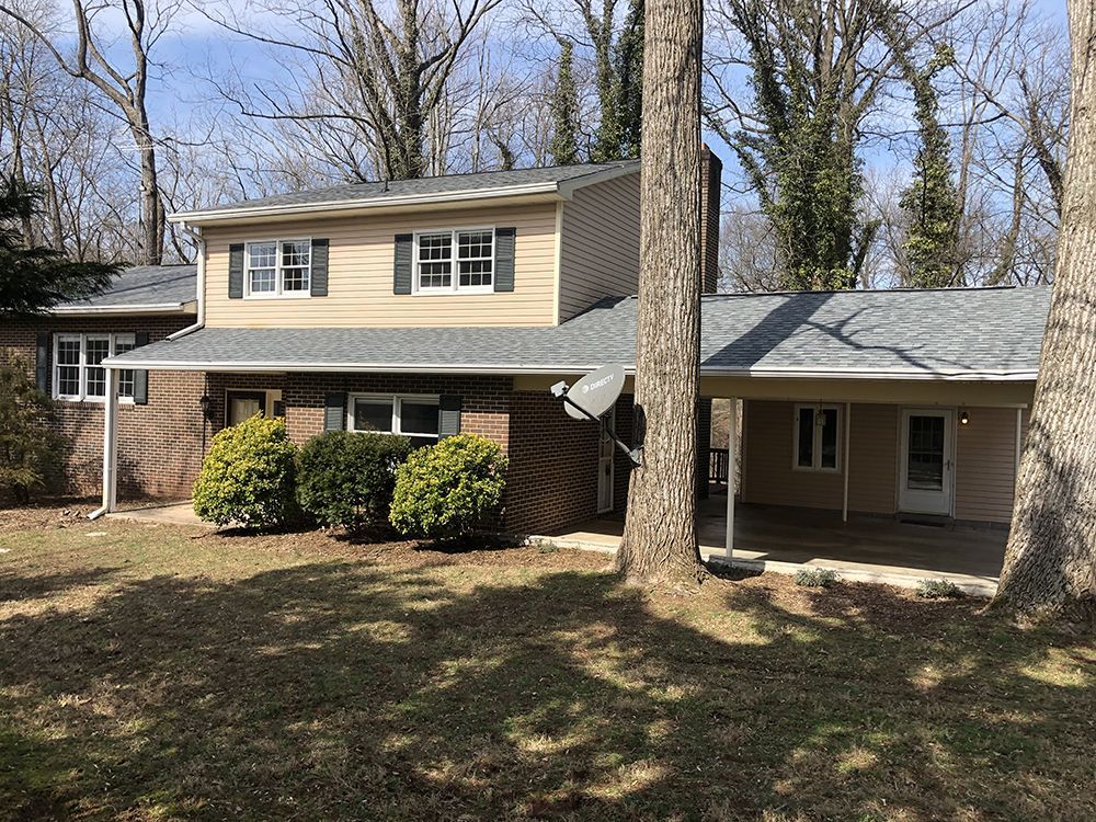 A large house with a porch and trees in front of it.