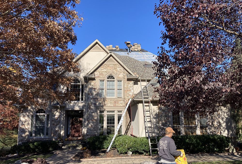 A man is sitting on a ladder in front of a large house.