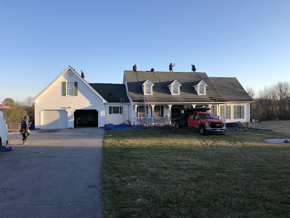 A large white house with a red truck parked in front of it.