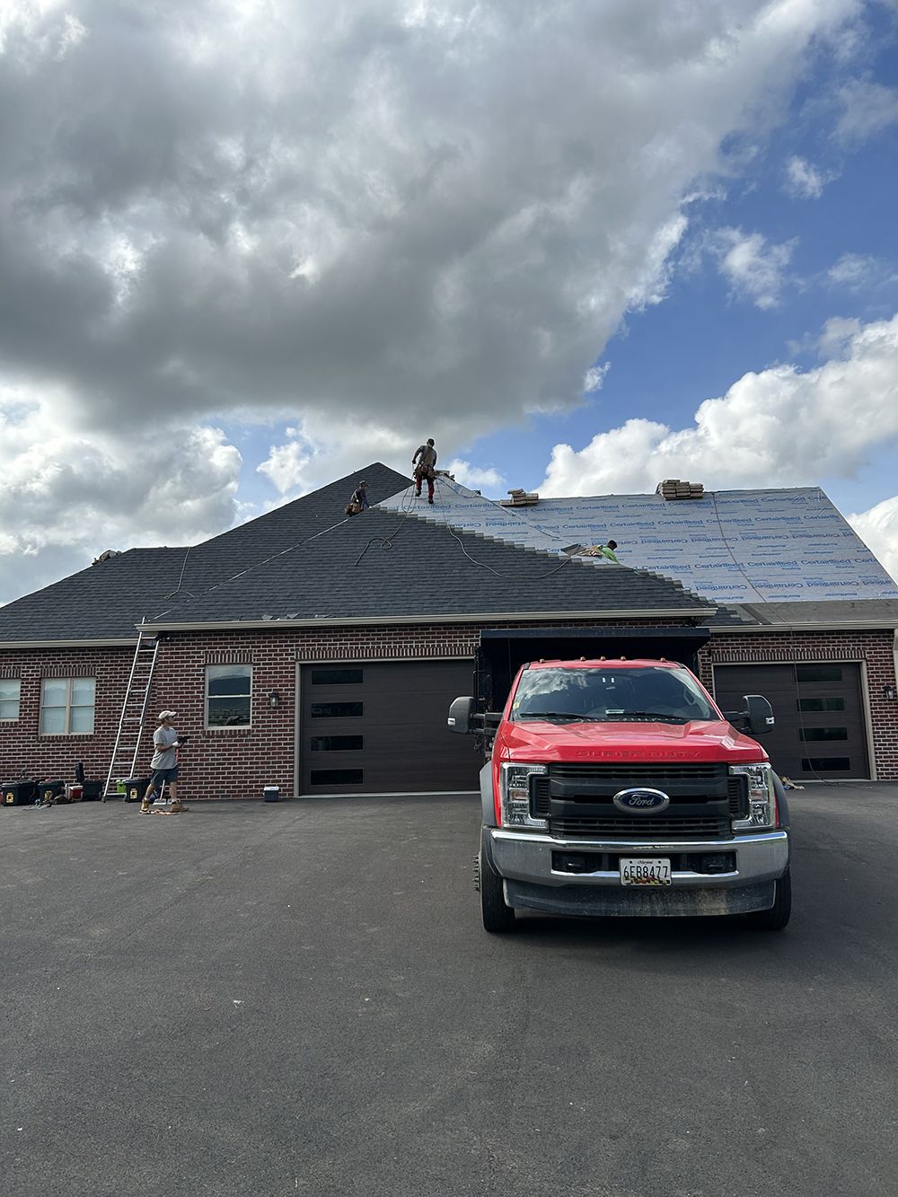 A red truck is parked in front of a house under construction.