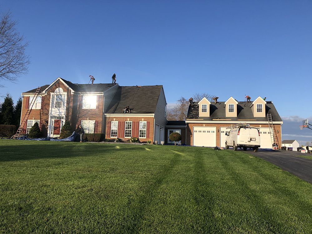 A large brick house with a large lawn in front of it.