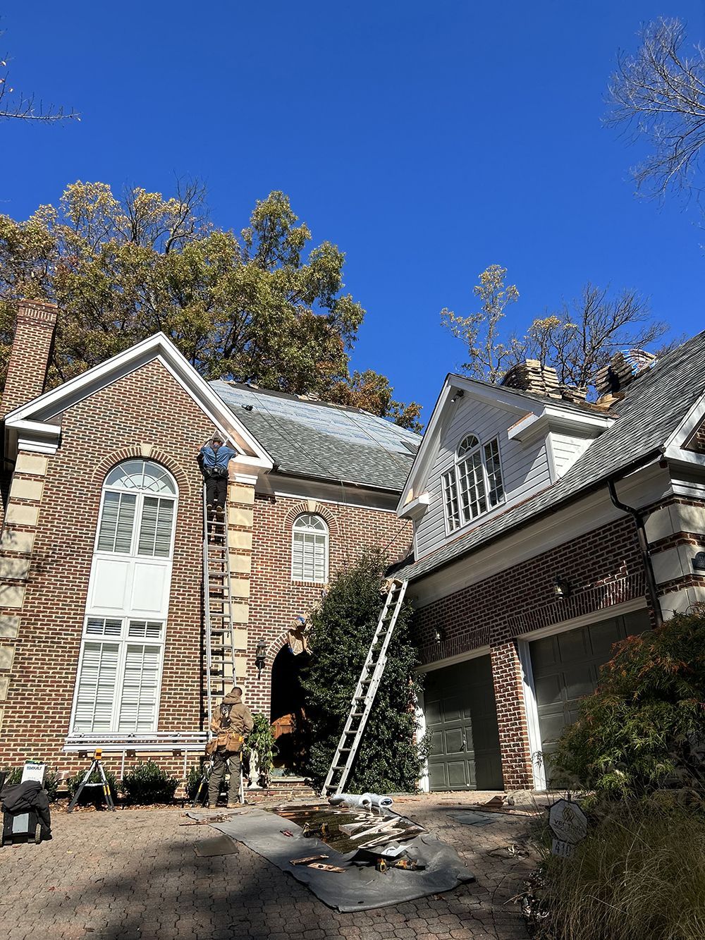 A man is working on the roof of a brick house.