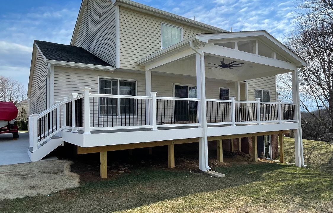A white house with a large white deck and a covered porch.