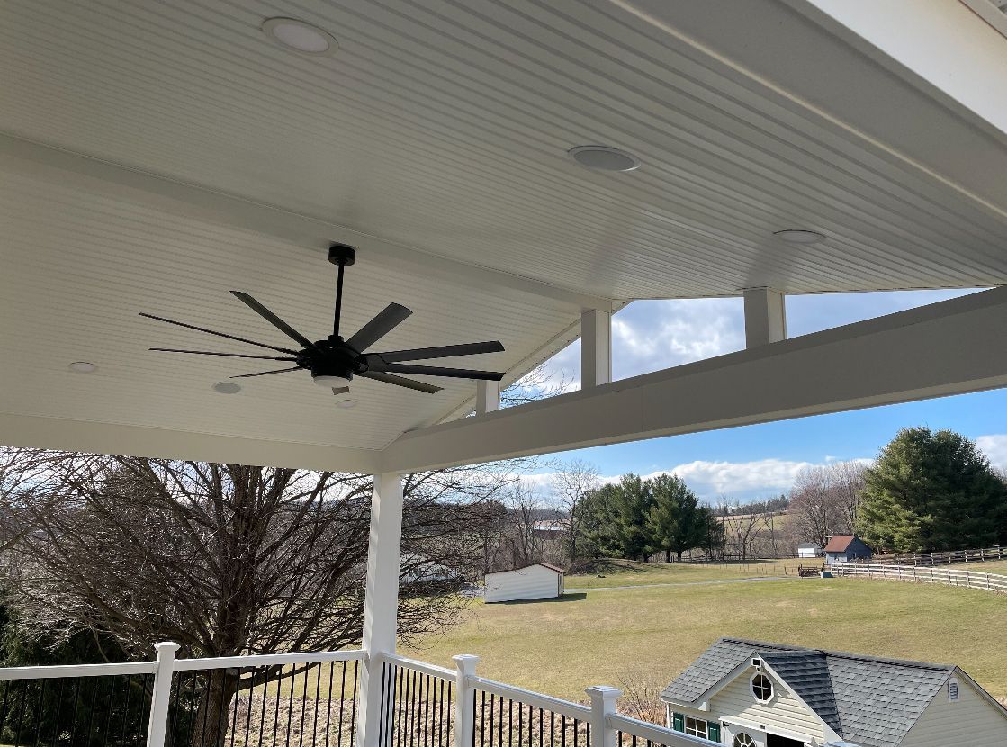 A ceiling fan is hanging from the ceiling of a porch.