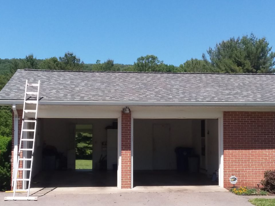 A ladder is sitting in front of a garage on a sunny day.