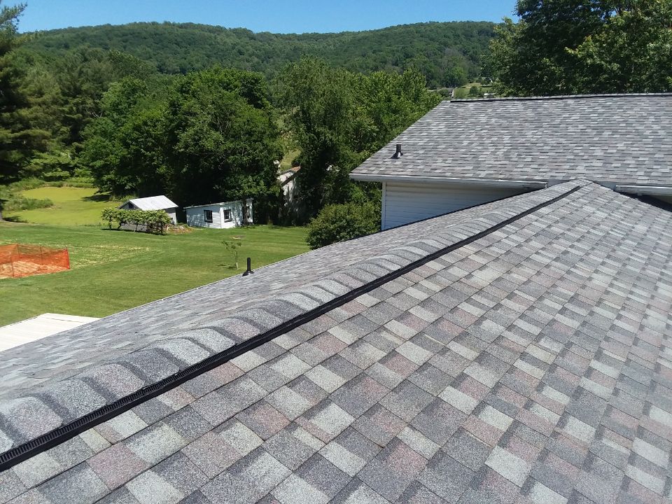A roof with a lot of shingles on it and a house in the background.