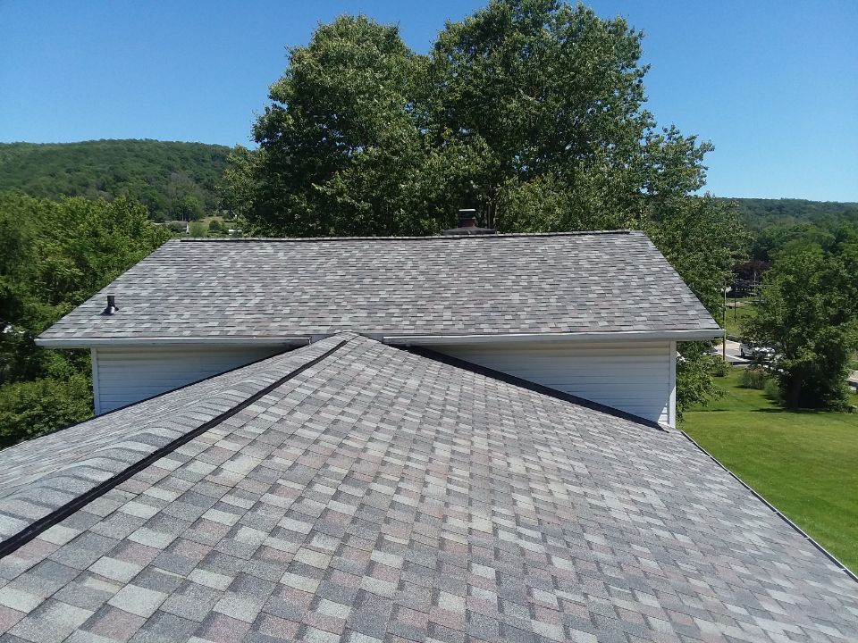 An aerial view of a roof of a house with trees in the background.