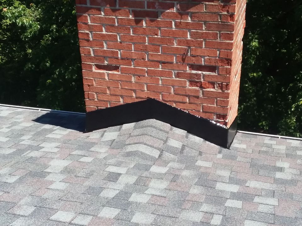 A brick chimney is sitting on top of a roof