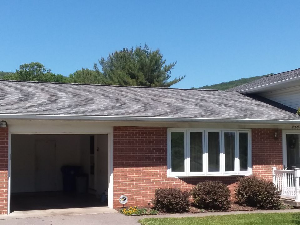 A brick house with a garage and a gray roof