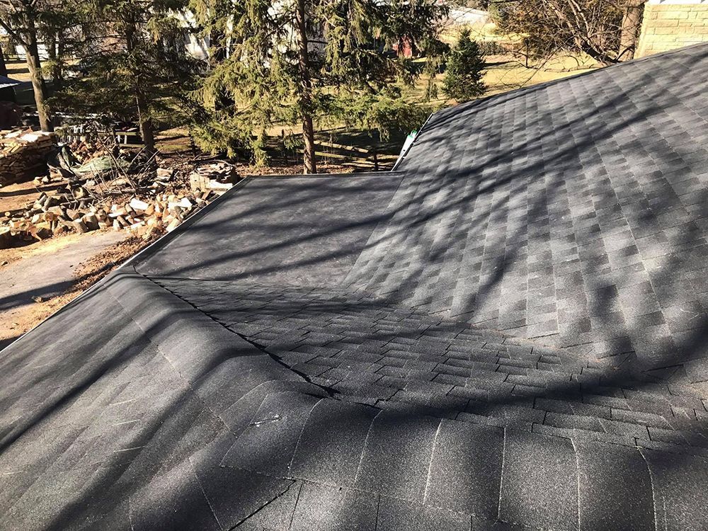 A close up of a black roof with trees in the background.