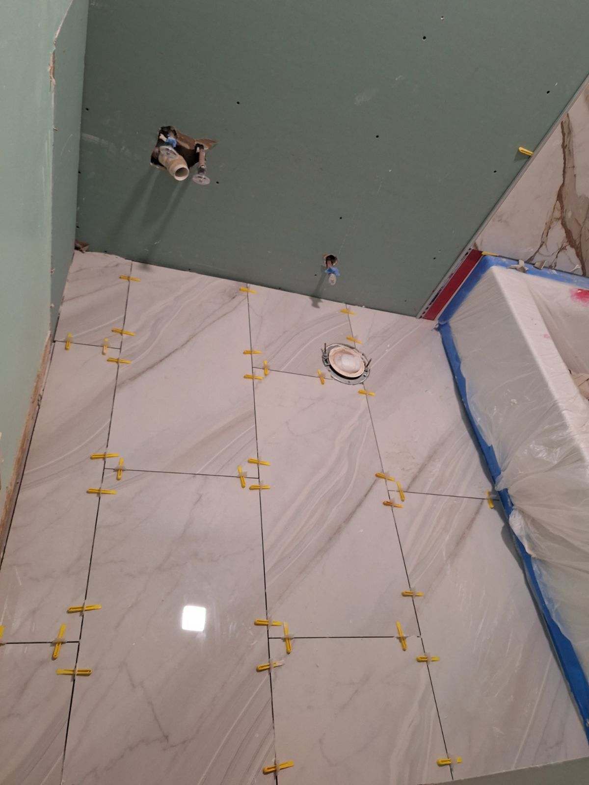 A bathroom floor is being tiled with yellow spacers.