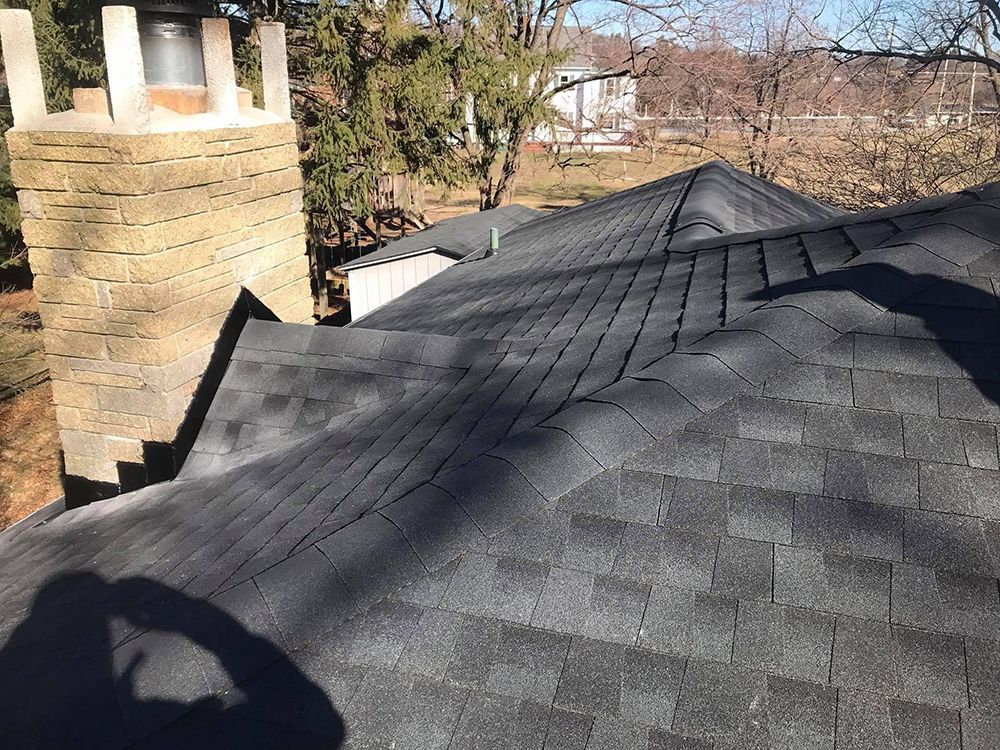 A roof with a chimney and a shadow of a person on it.
