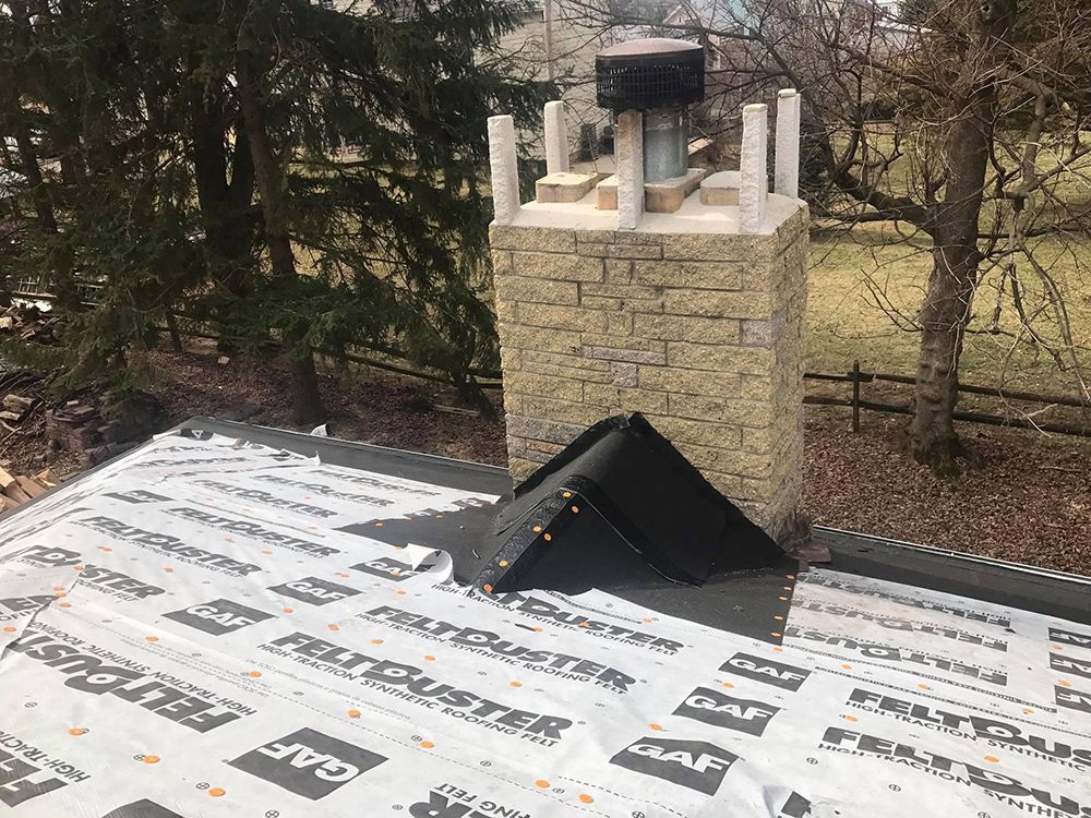 A chimney is sitting on top of a roof covered in roofing paper.