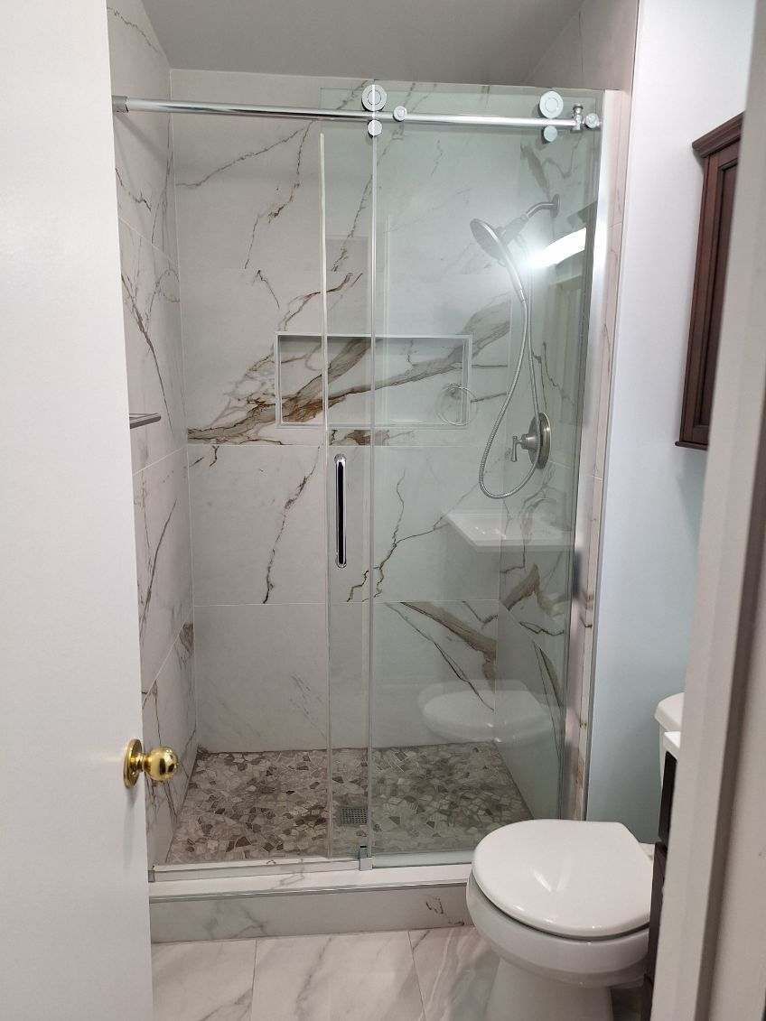A bathroom with a toilet , sink , shower and sliding glass door.