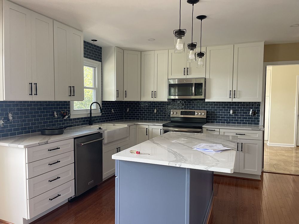 A kitchen with white cabinets , stainless steel appliances , and a large island.