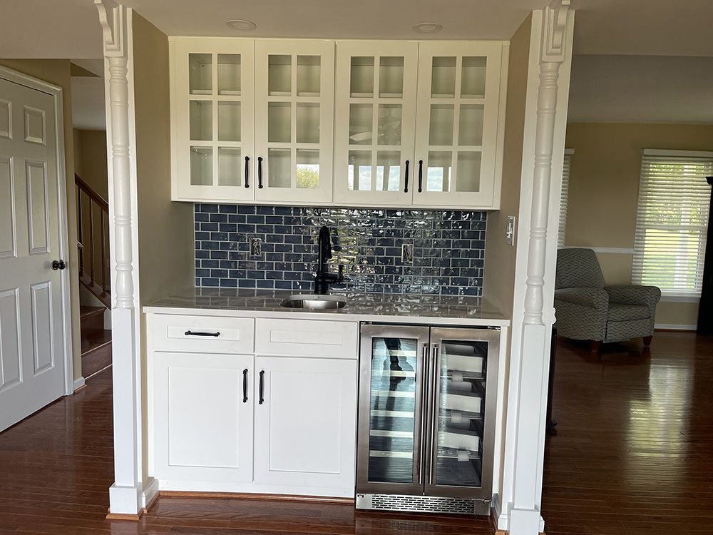 A kitchen with white cabinets and a wine cooler.