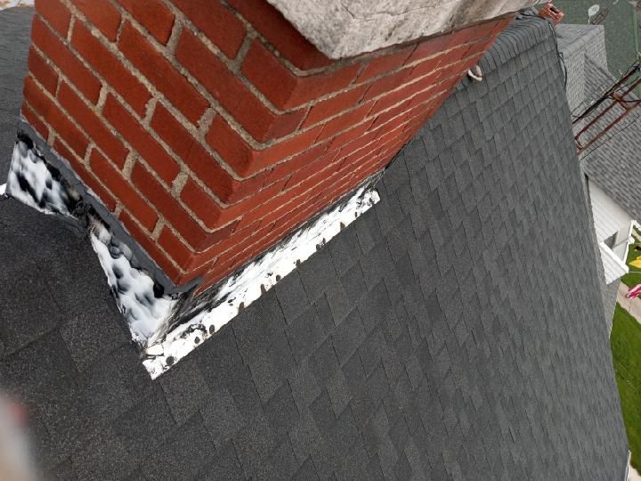 A brick chimney sitting on top of a black roof