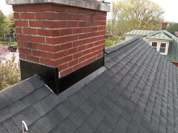 A brick chimney on top of a black roof