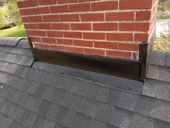 A brick chimney is sitting on top of a roof.