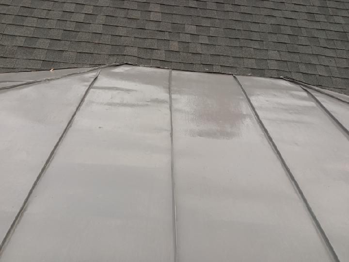 A close up of a metal roof with a roof in the background.
