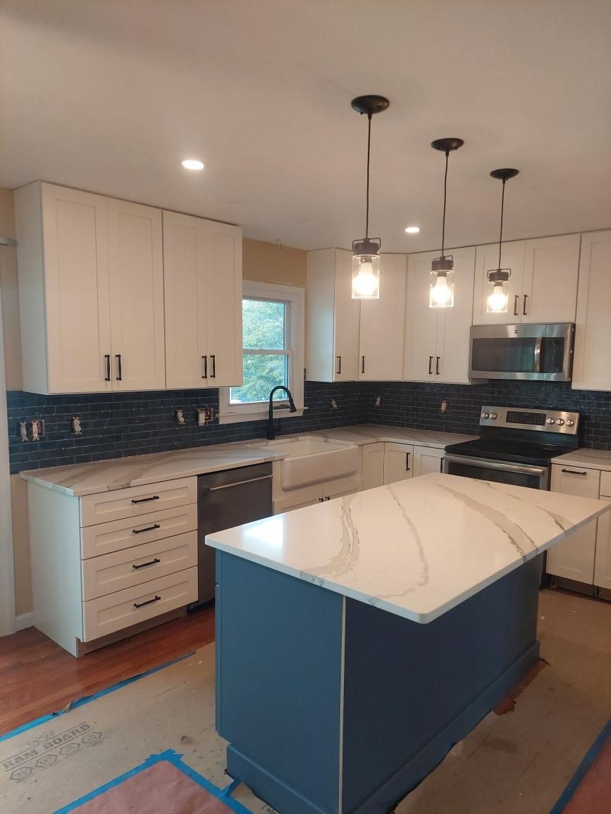 A kitchen with white cabinets and a blue island in the middle