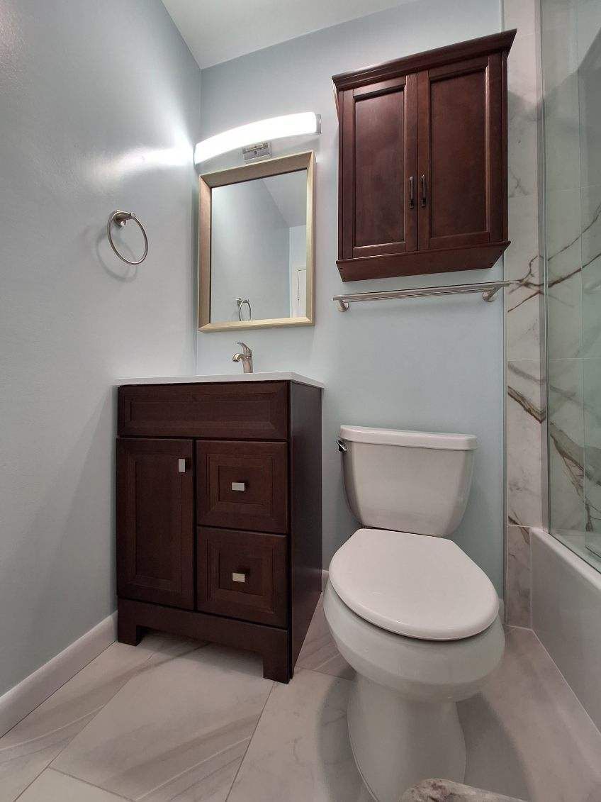 A bathroom with a toilet , sink and mirror.