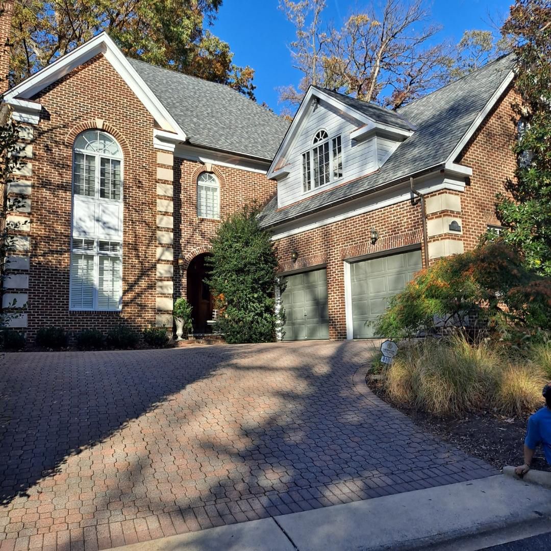 A large brick house with a gray roof and a brick driveway.