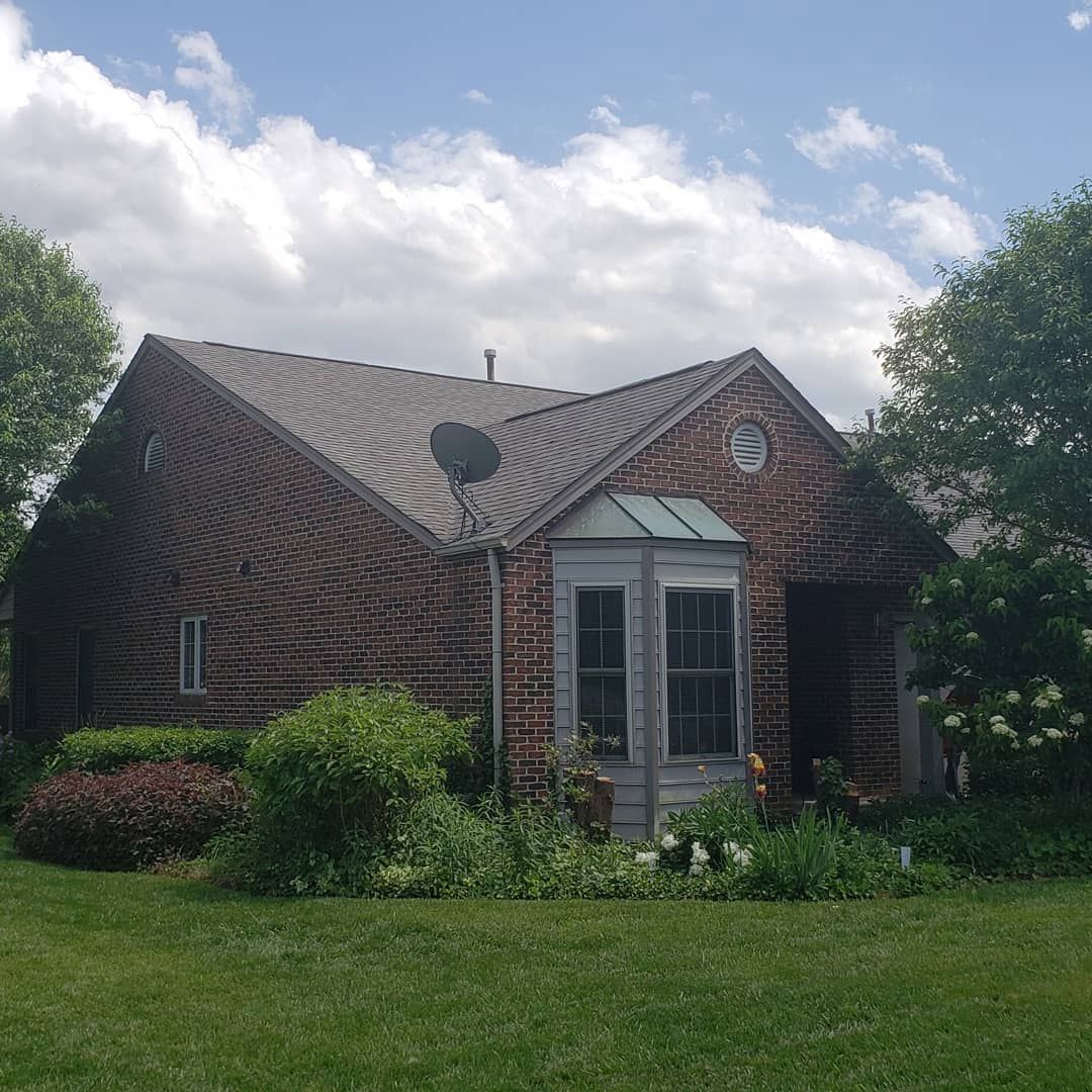 A small brick house with a satellite dish on the roof