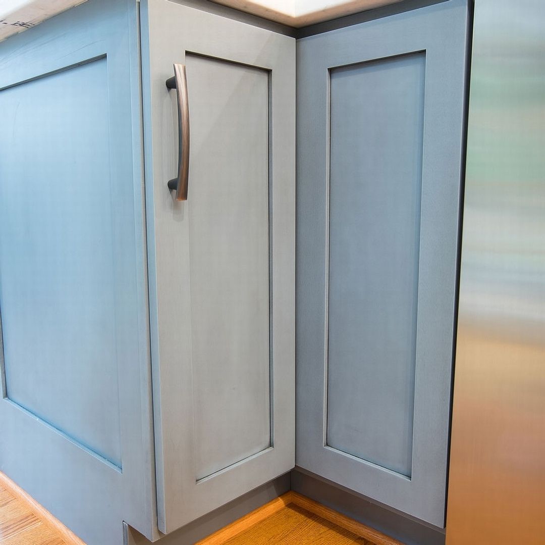 A kitchen with blue cabinets and a stainless steel refrigerator