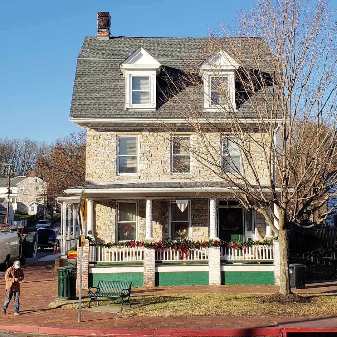 A large house with a gray roof and a green porch