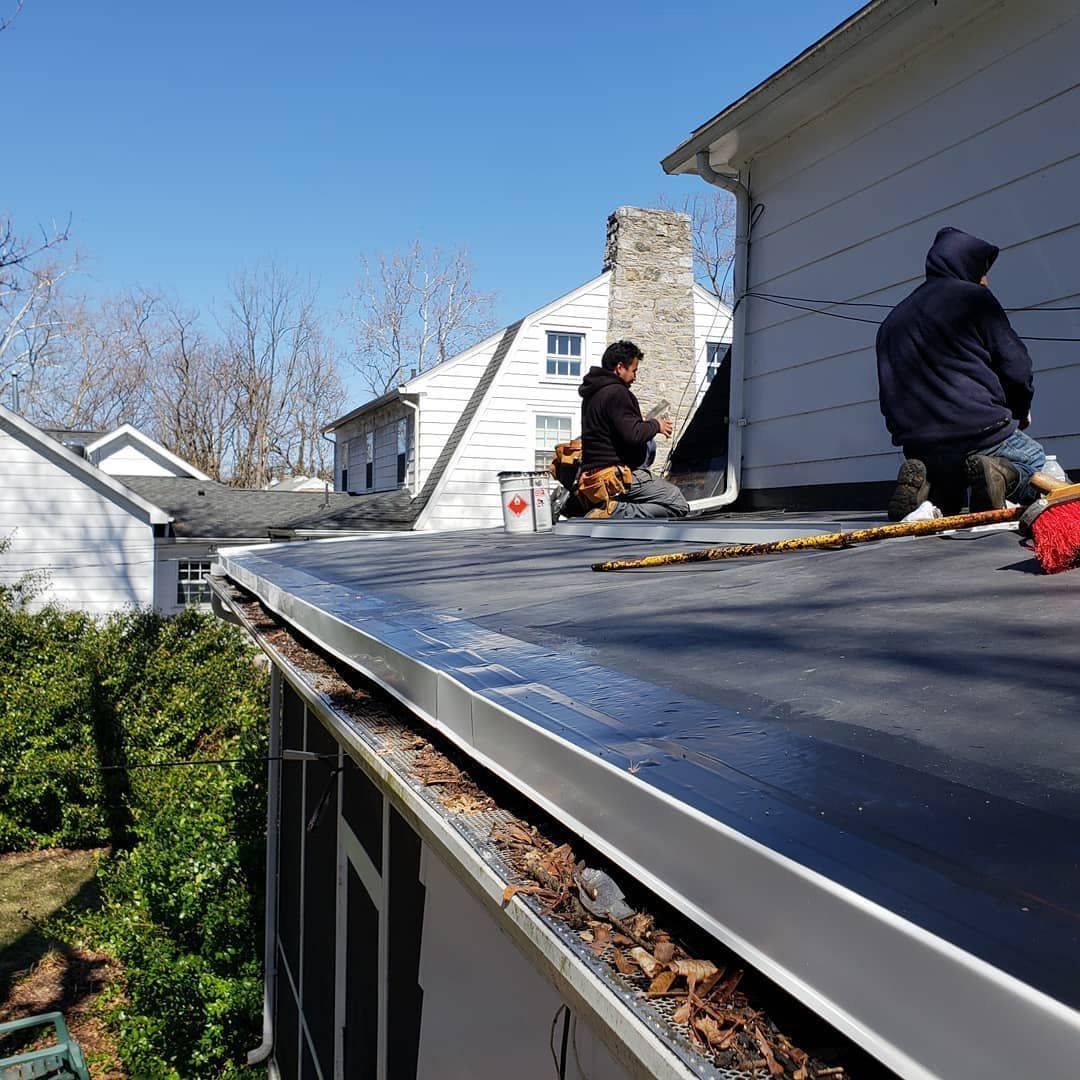 Two men are working on the roof of a house.