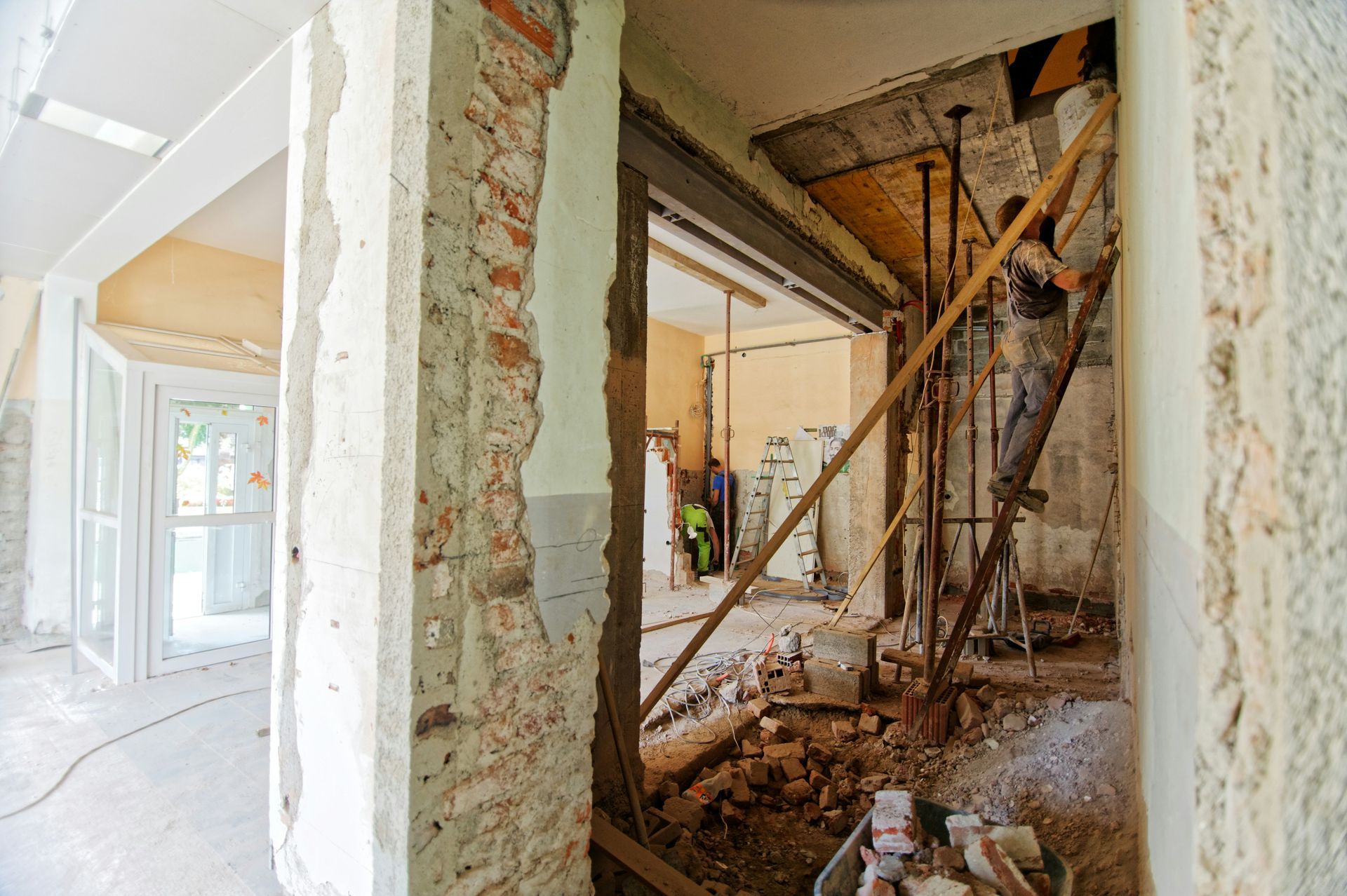 Partially demolished interior with exposed walls, debris, and construction scaffolding in a narrow hallway