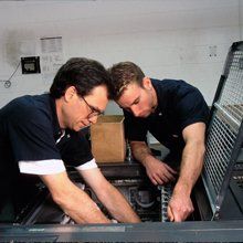2 Men repairing a printing machine