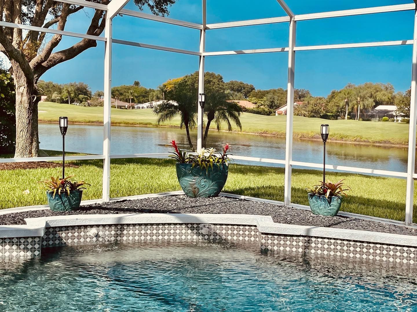 Pool enclosure with lake view; turquoise planters, water, sky, and white framing.