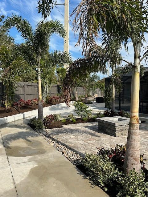 Landscaped outdoor area with palm trees, pavers, and flowerbeds.
