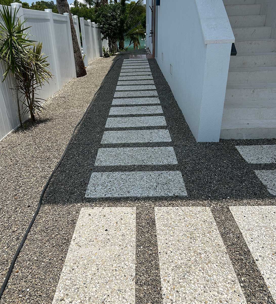 A stone walkway leading to a white building with stairs.