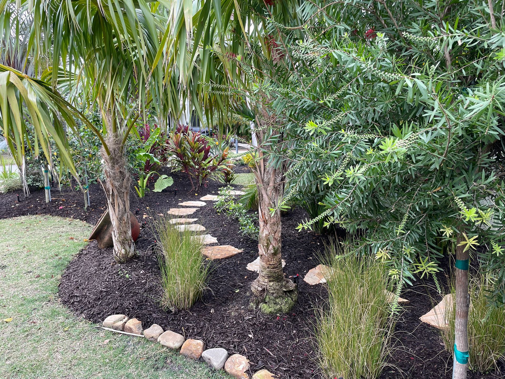 A lush green garden with trees and a stone path.