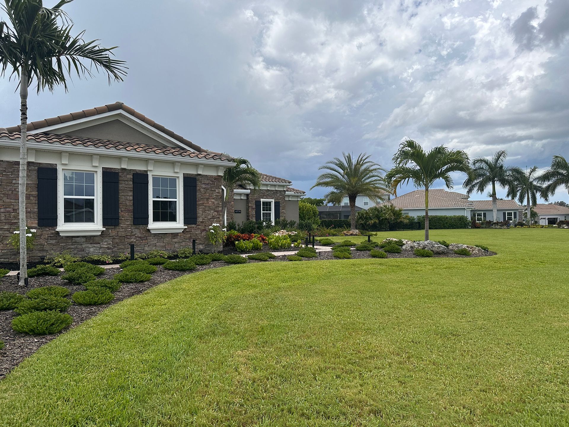 A house with a large lawn in front of it and palm trees.
