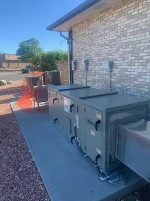 Commercial HVAC units on a concrete pad next to a brick building.