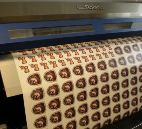 Roland printer printing rows of brown and cream-colored sticker designs.