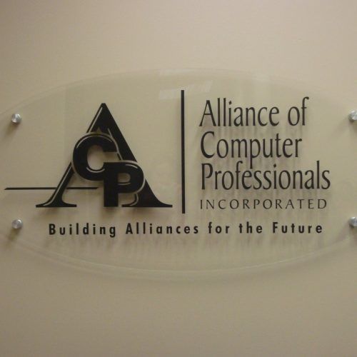Logo for Alliance of Computer Professionals, "ACP" in a black stylized design on a clear plaque, mounted to a wall.