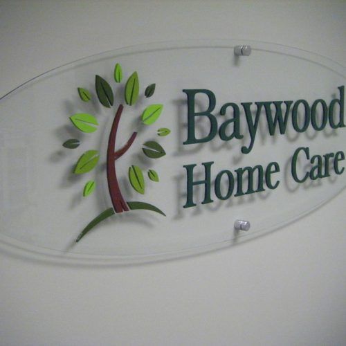 Clear oval sign for Baywood Home Care with a tree logo and dark green text.