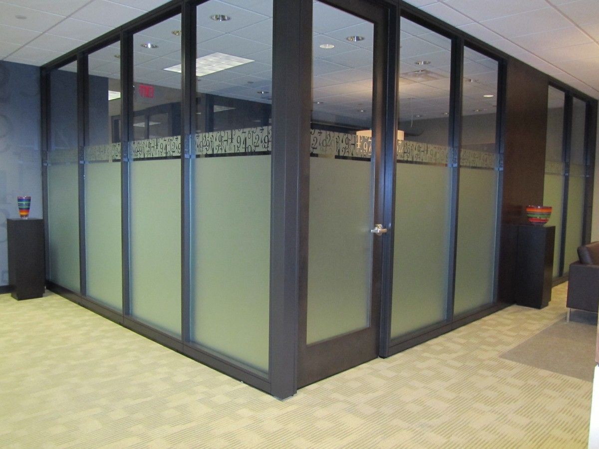 Glass-walled office with frosted lower panels, dark frame, and patterned top. Beige carpet.