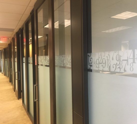 Hallway with frosted glass office doors, brown frames, and a decorative number pattern.