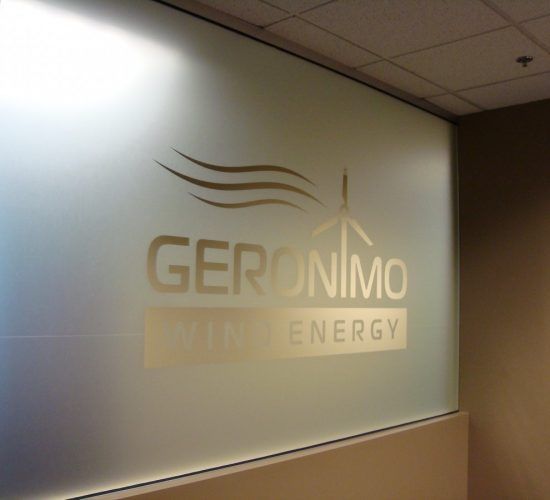 Logo of Geronimo Wind Energy on frosted glass window in a building.
