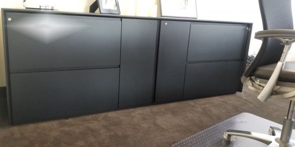Dark gray storage cabinets on a brown carpet. A desk chair is in the right corner.