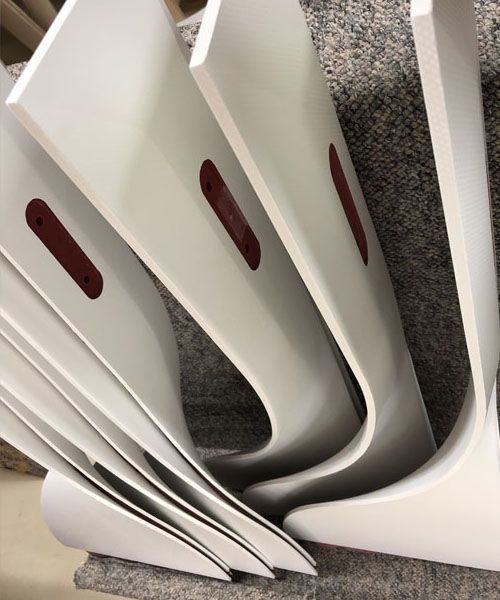 White curved pieces with reddish-brown insets are stacked, possibly components of furniture.